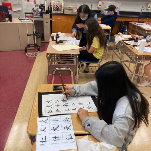 Students writing calligraphy.